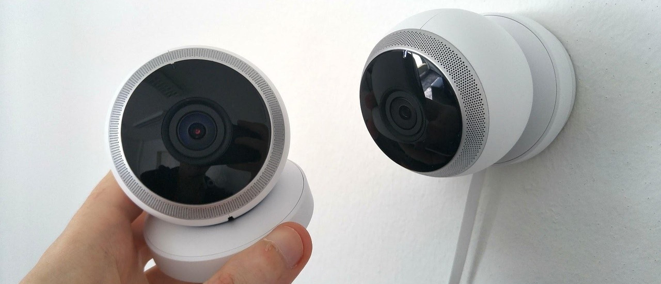 Hand plaatst een witte draadloze beveiligingscamera op een muurbeugel, klaar voor installatie