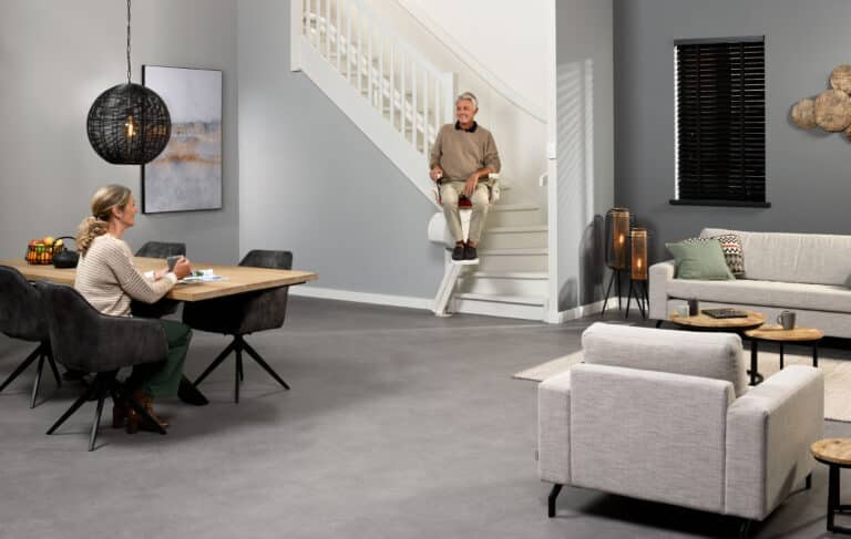 Senior gebruikt een Otolift traplift op een trap in de woonkamer